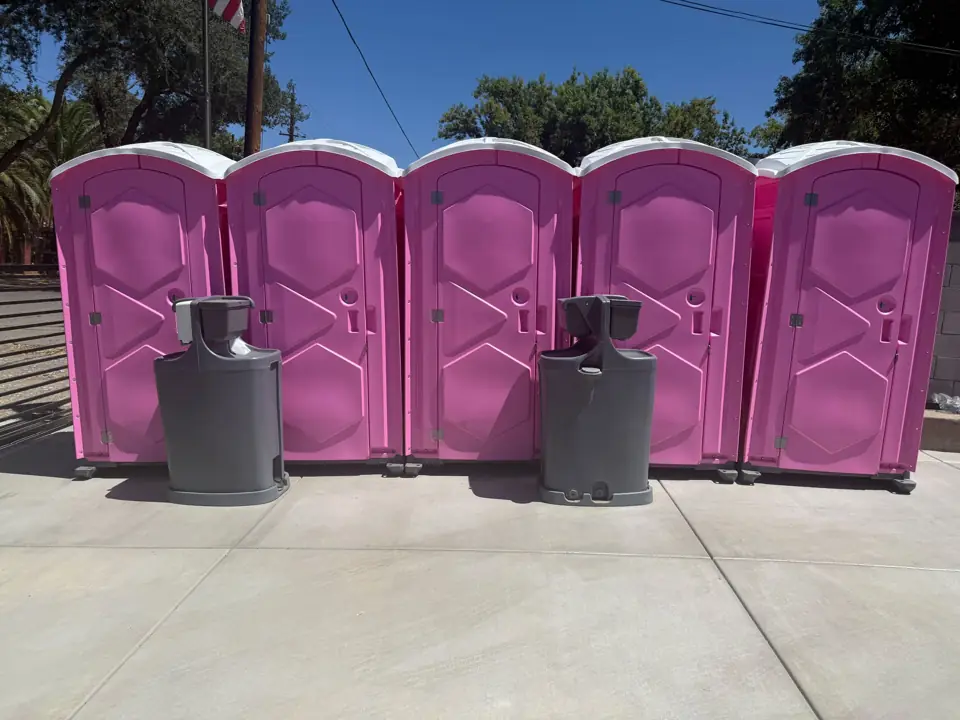Row of pink event porta potties with two hand wash stations in front